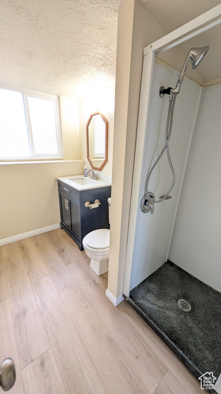 Bathroom with vanity, hardwood / wood-style floors, toilet, and a shower