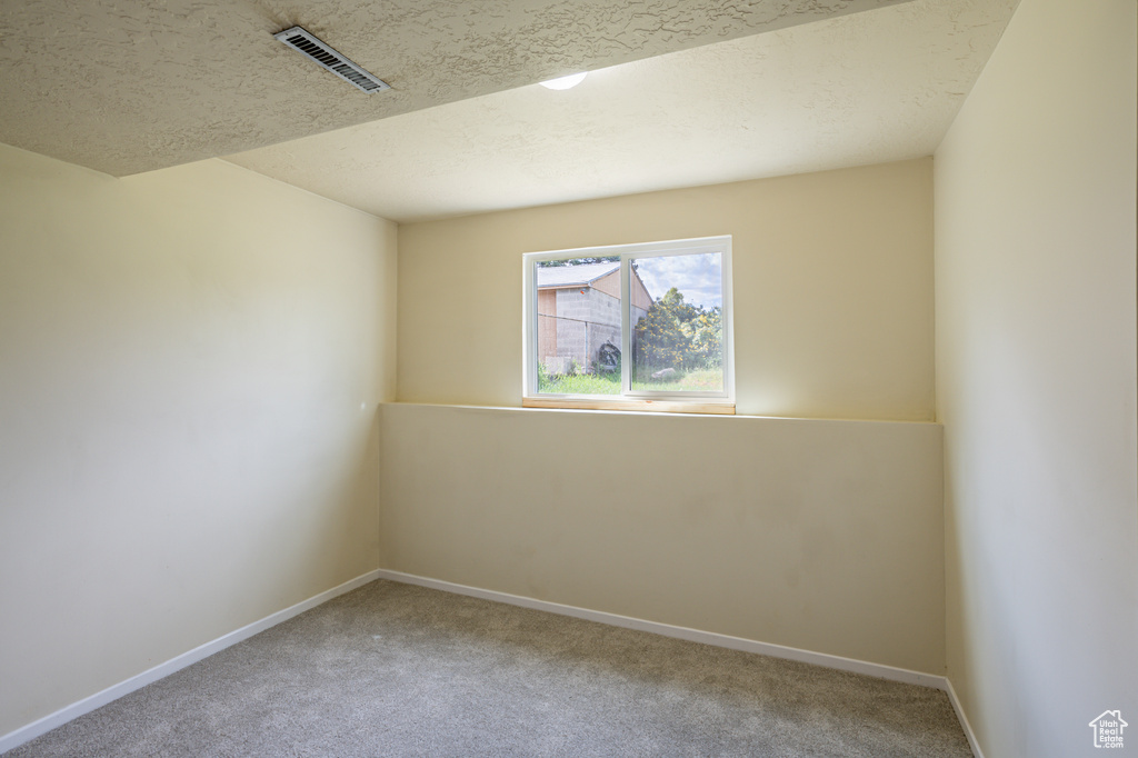 Spare room with a textured ceiling and carpet flooring