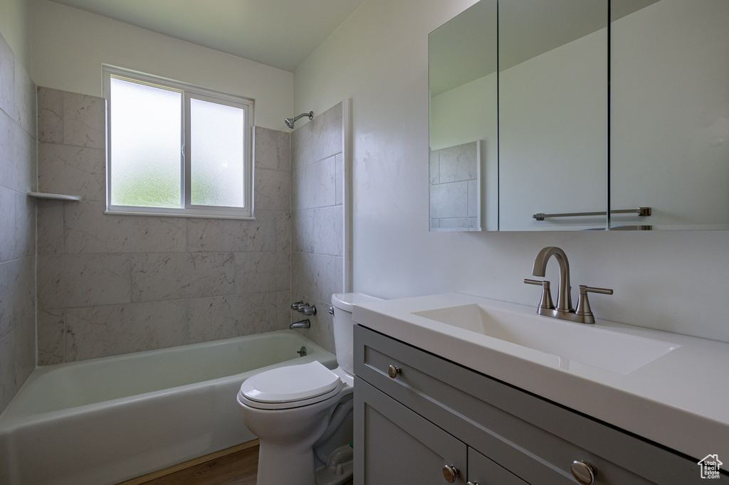 Full bathroom featuring tiled shower / bath, hardwood / wood-style flooring, toilet, and vanity