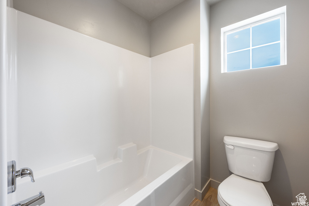 Bathroom featuring shower / tub combination, toilet, and hardwood / wood-style flooring