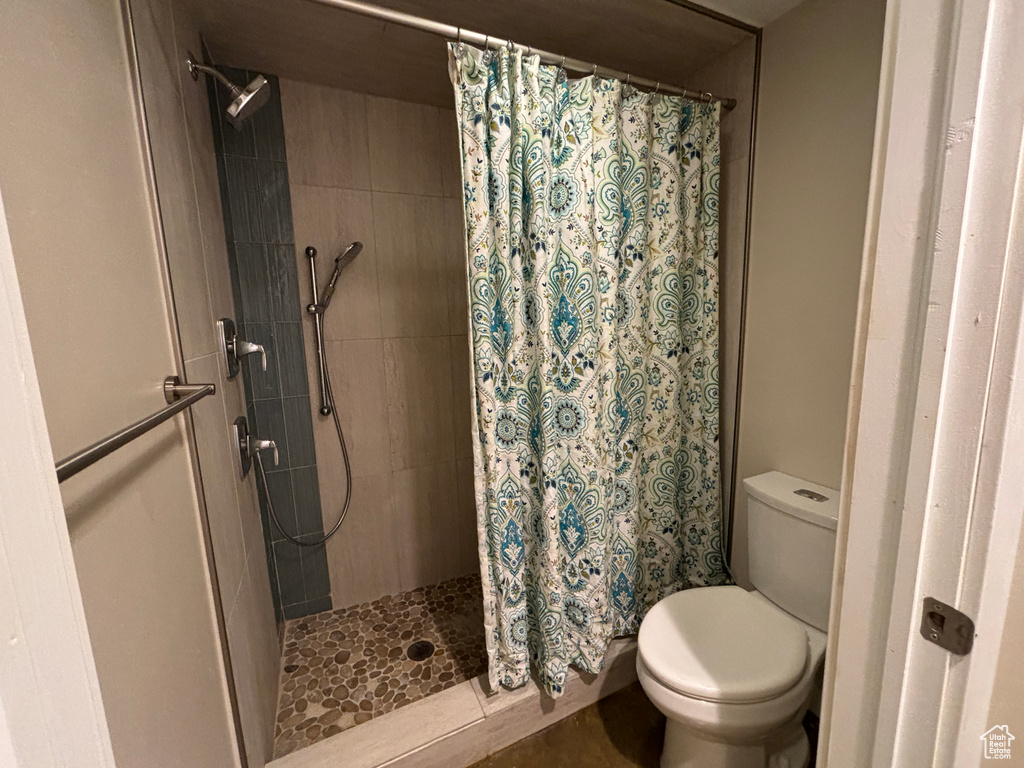 Bathroom featuring a shower with curtain and toilet