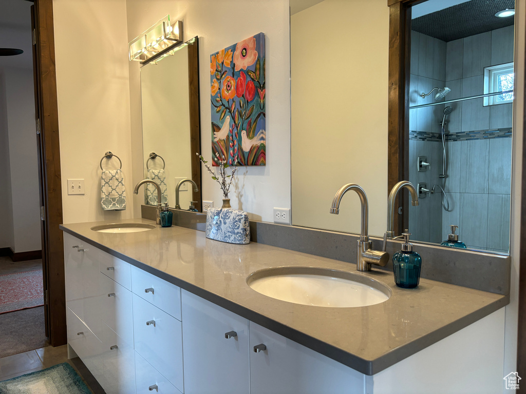 Bathroom with tiled shower and dual vanity