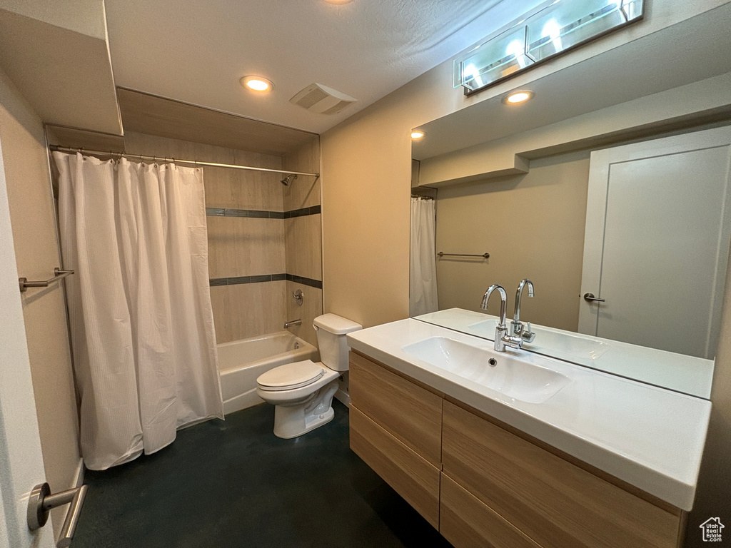 Full bathroom featuring vanity with extensive cabinet space, shower / bath combination with curtain, and toilet