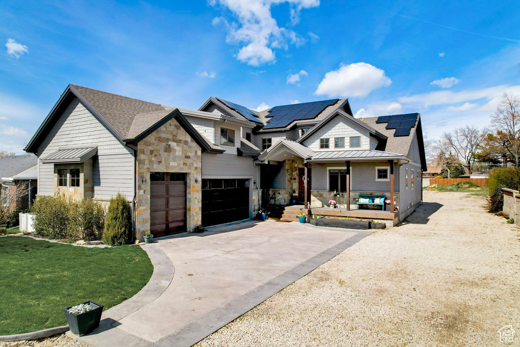 View of front of home featuring a front lawn, a garage, and solar panels