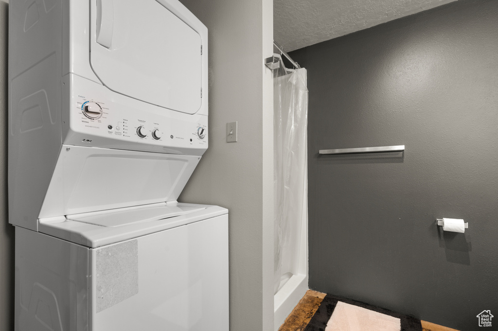 Clothes washing area featuring tile floors, a textured ceiling, and stacked washer and dryer