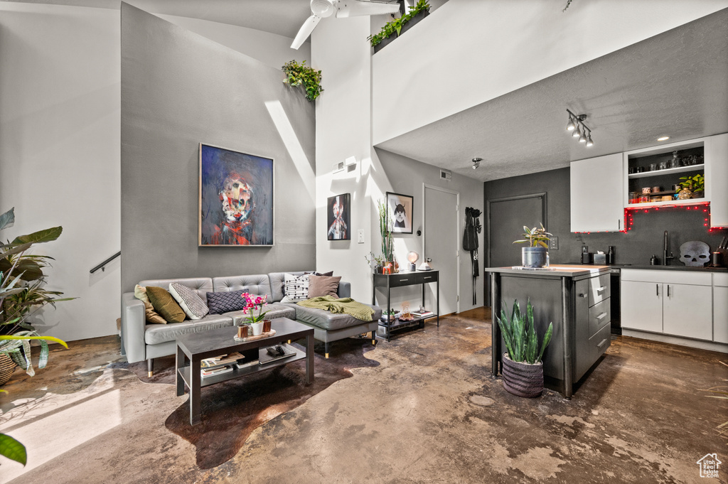 Living room featuring ceiling fan, concrete floors, a textured ceiling, and rail lighting