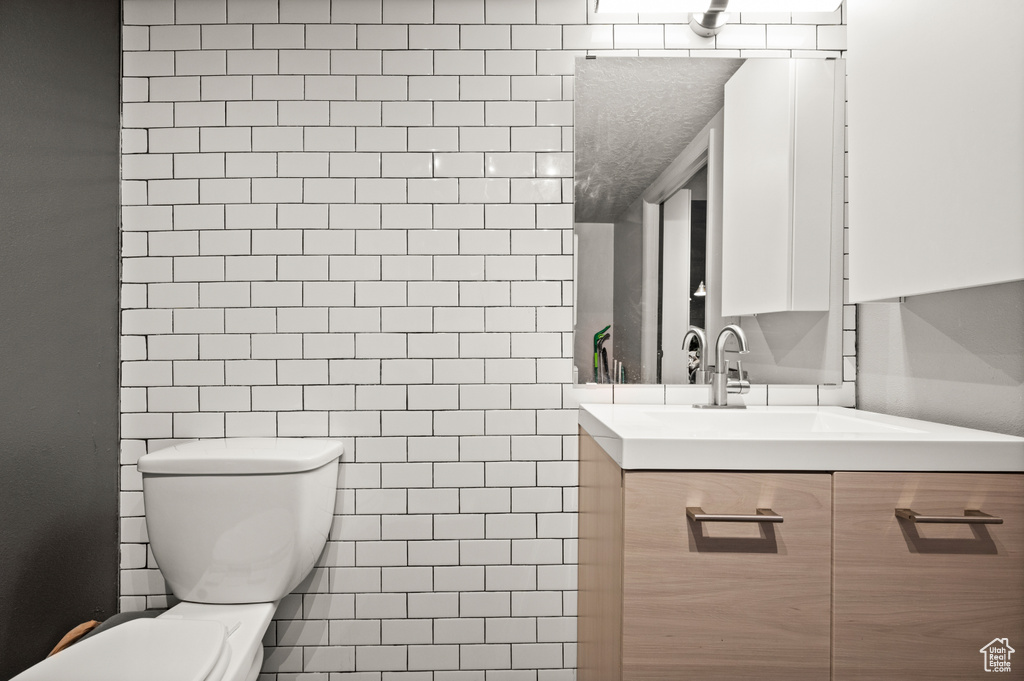 Bathroom with tile walls, toilet, and vanity