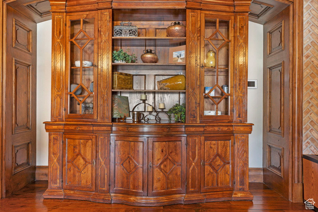 Bar featuring dark hardwood / wood-style flooring and crown molding