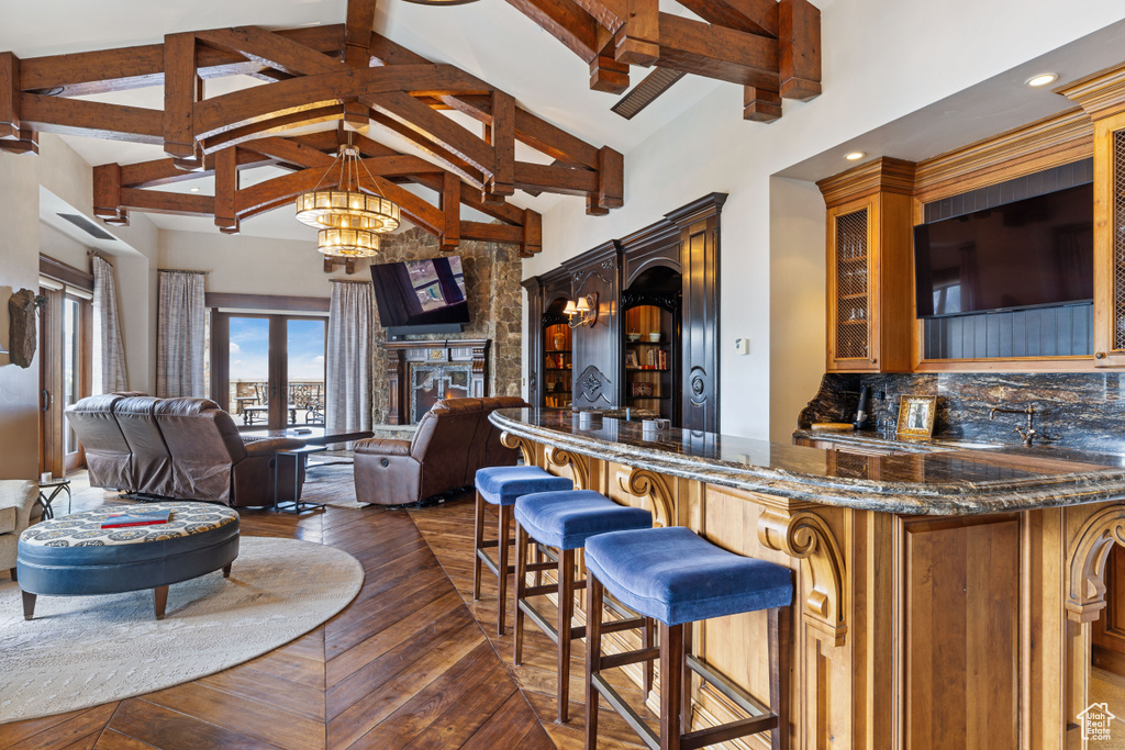 Interior space featuring a towering ceiling, a fireplace, a kitchen bar, and dark stone countertops