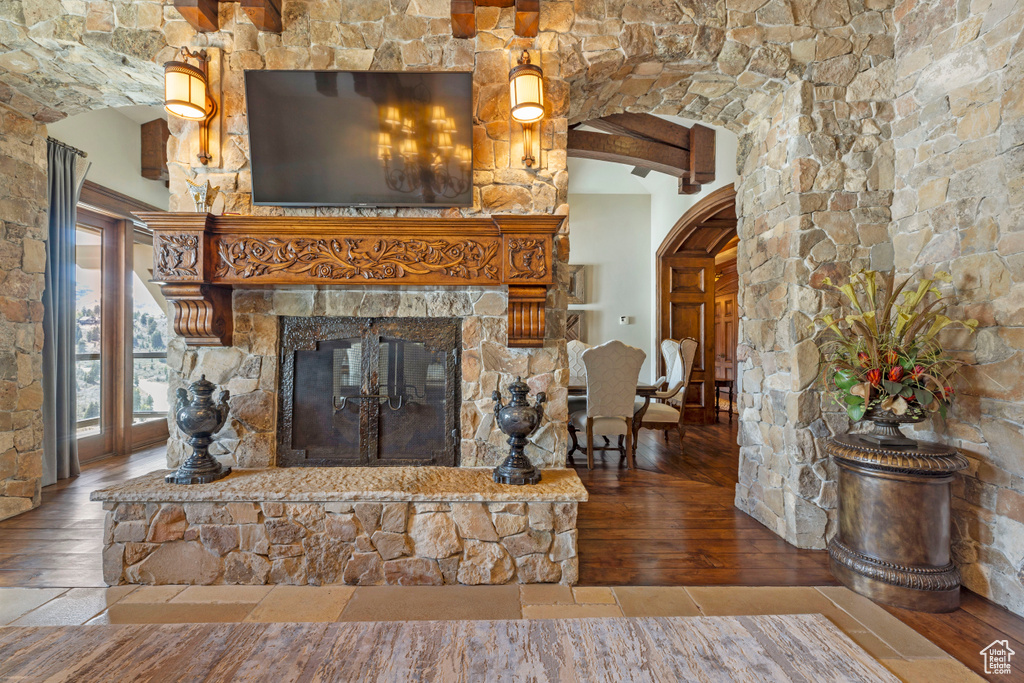 Unfurnished living room featuring beamed ceiling, hardwood / wood-style flooring, and a fireplace