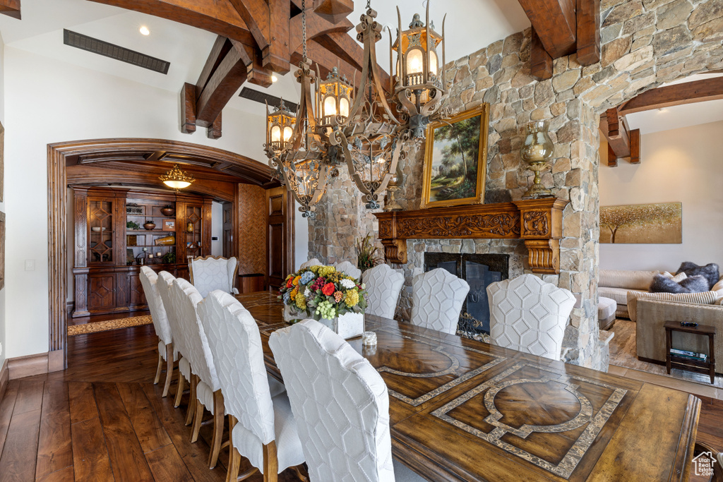 Dining area featuring beamed ceiling, high vaulted ceiling, an inviting chandelier, and hardwood / wood-style flooring