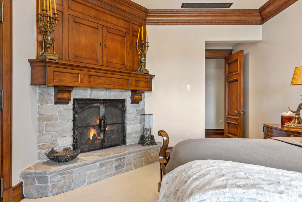 Carpeted bedroom featuring ornamental molding and a fireplace