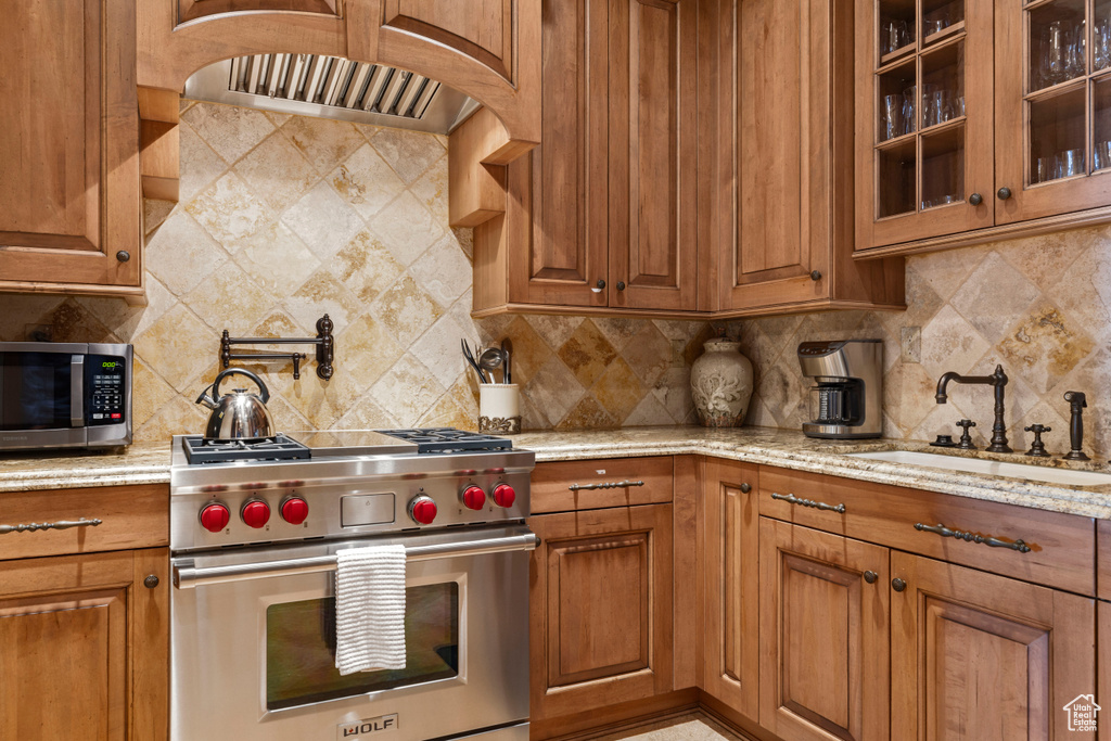 Kitchen featuring light stone countertops, sink, tasteful backsplash, and appliances with stainless steel finishes