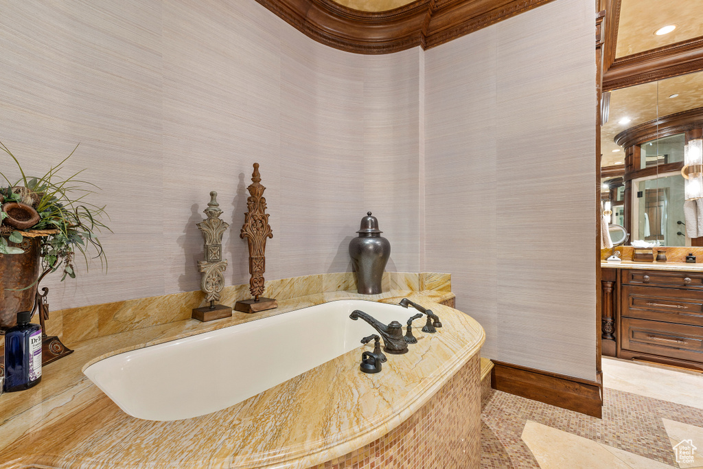 Bathroom featuring crown molding, a bath to relax in, tile floors, tile walls, and vanity