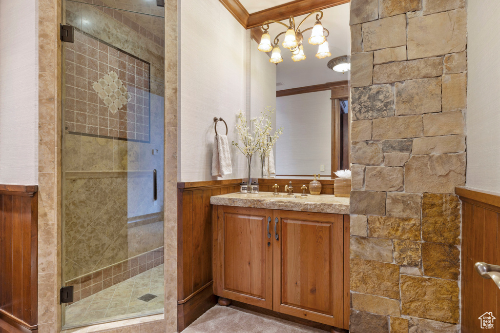 Bathroom with a shower with door, ornamental molding, oversized vanity, and a chandelier