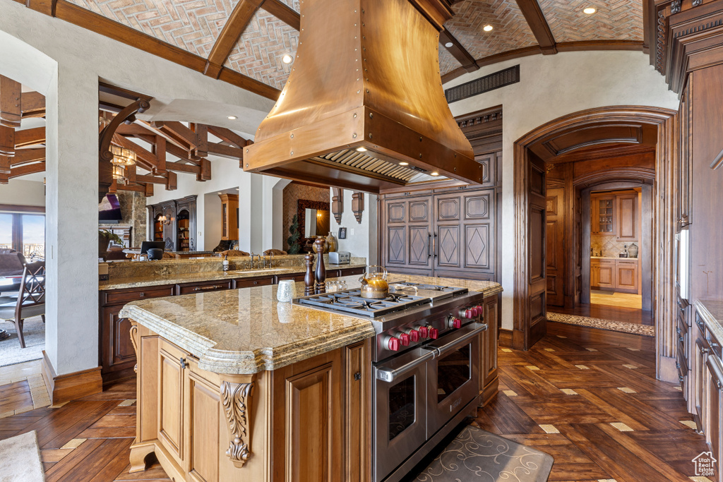 Kitchen featuring dark parquet floors, custom exhaust hood, double oven range, a kitchen island, and a high ceiling