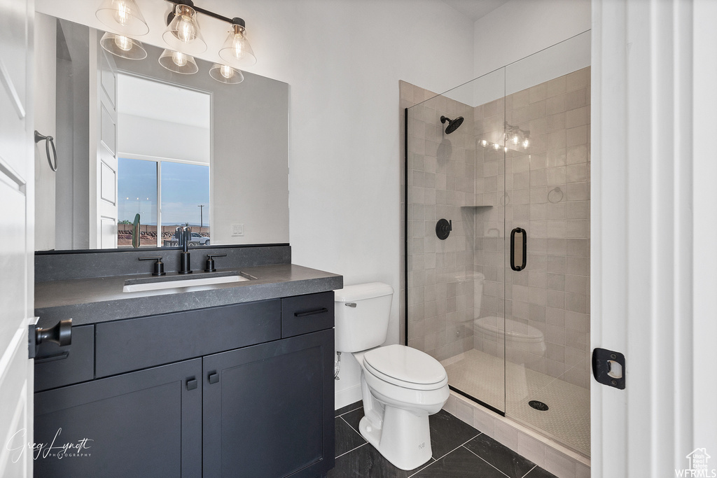 Bathroom with tile flooring, an enclosed shower, vanity, and toilet