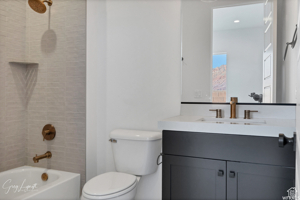 Full bathroom with toilet, tiled shower / bath combo, and large vanity