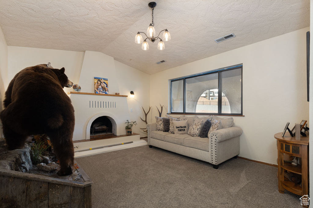 Carpeted living room featuring a notable chandelier, a textured ceiling, and lofted ceiling