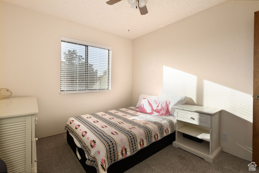 Bedroom featuring a textured ceiling, ceiling fan, and carpet floors