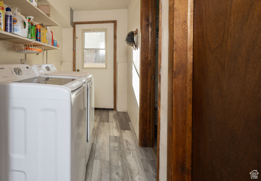 Laundry area with separate washer and dryer and light hardwood / wood-style flooring