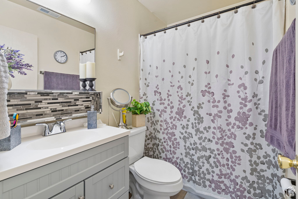 Bathroom featuring tasteful backsplash, oversized vanity, and toilet