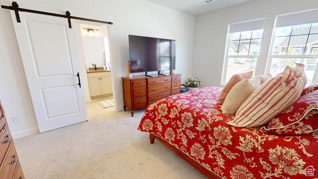 Carpeted bedroom with a barn door, sink, and ensuite bath