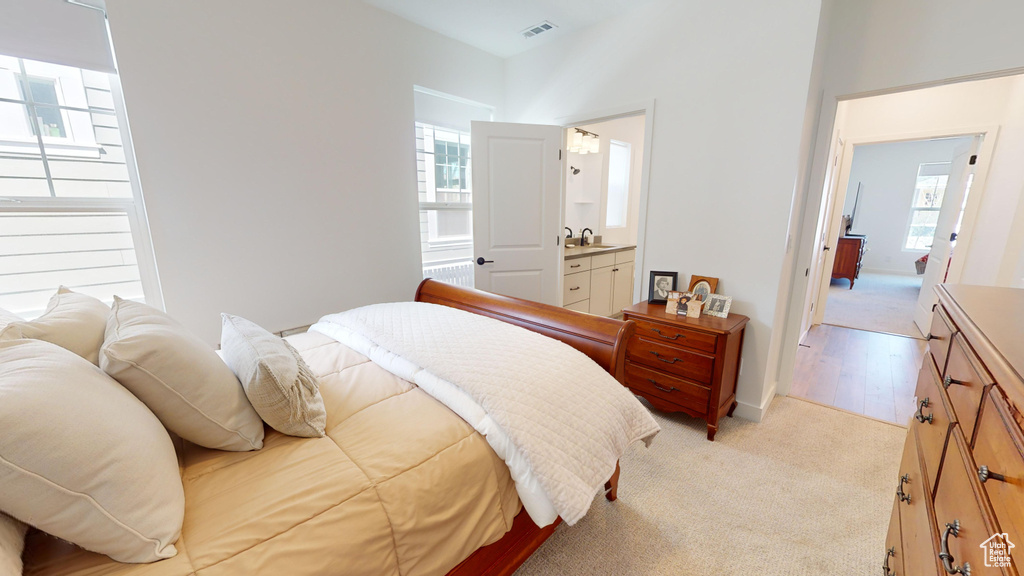 Bedroom with sink, connected bathroom, and light hardwood / wood-style flooring