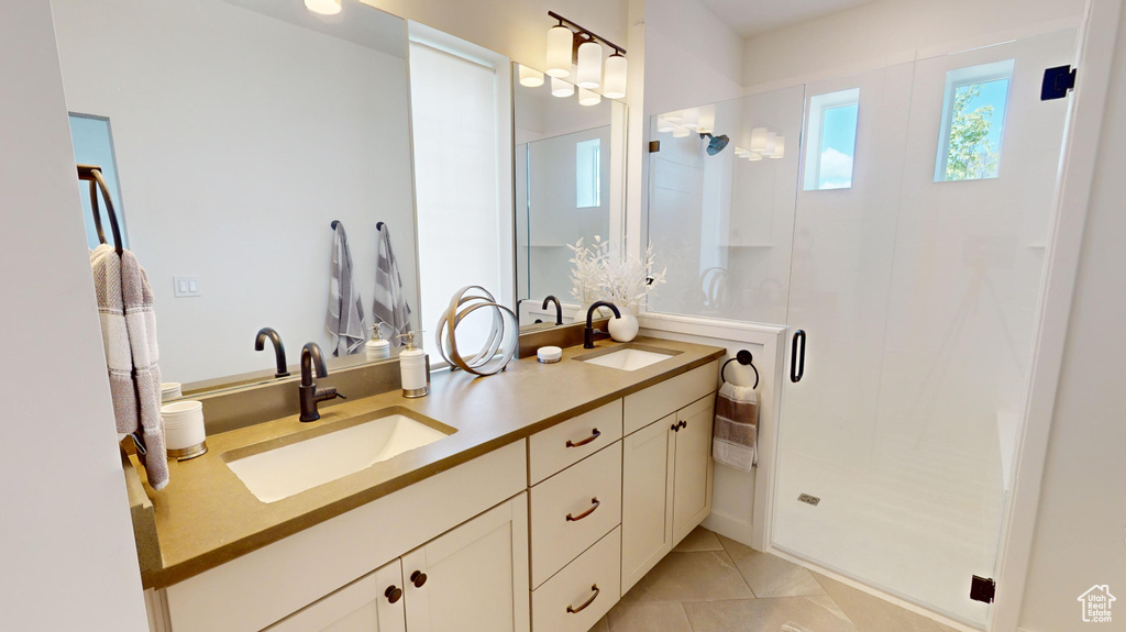 Bathroom with dual sinks, a shower with door, tile floors, and large vanity