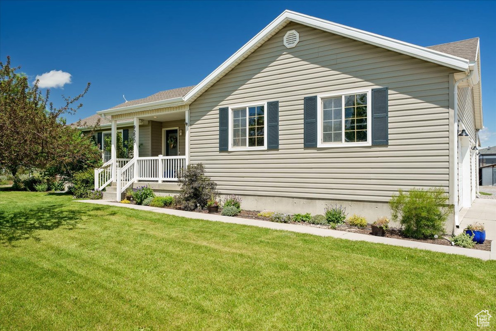 View of front facade featuring a garage, a front yard, and a porch