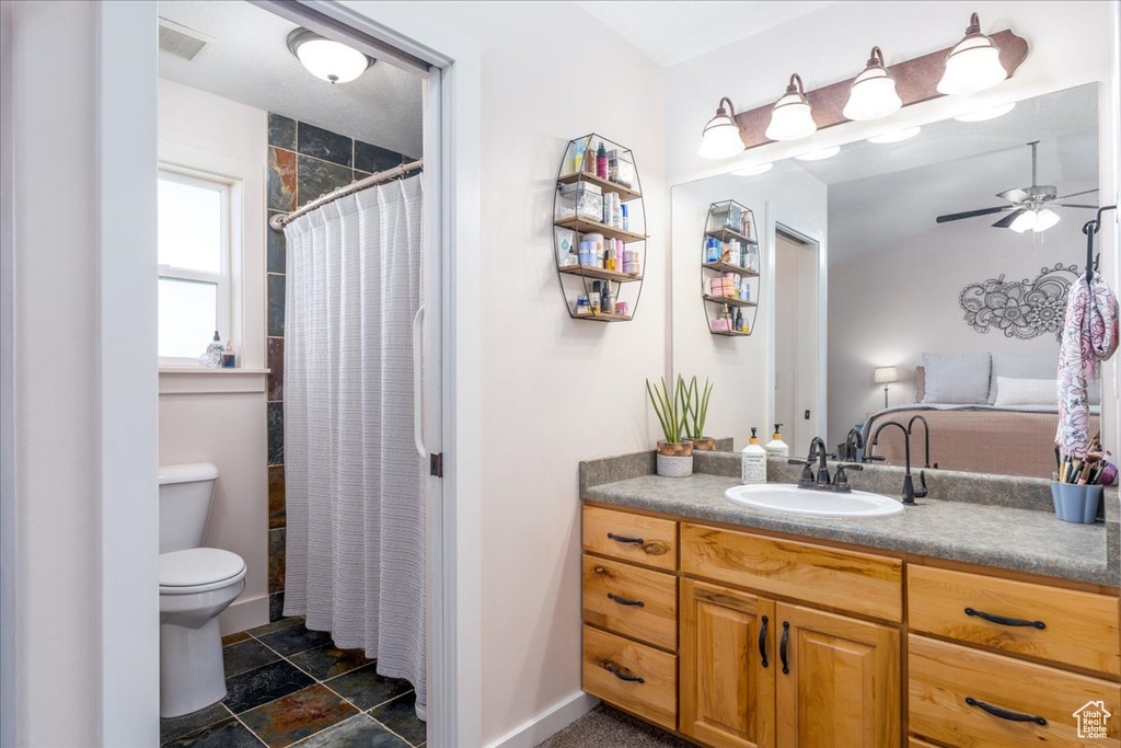 Bathroom featuring tile floors, ceiling fan, toilet, and large vanity