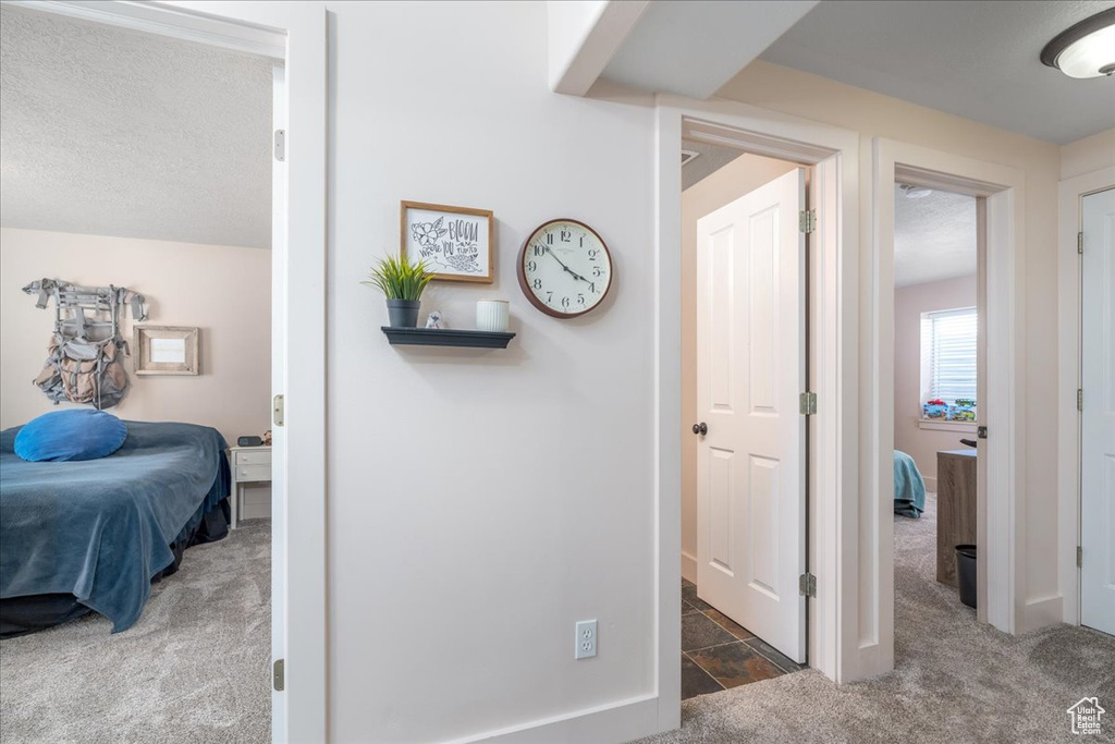 Corridor with a textured ceiling and dark carpet