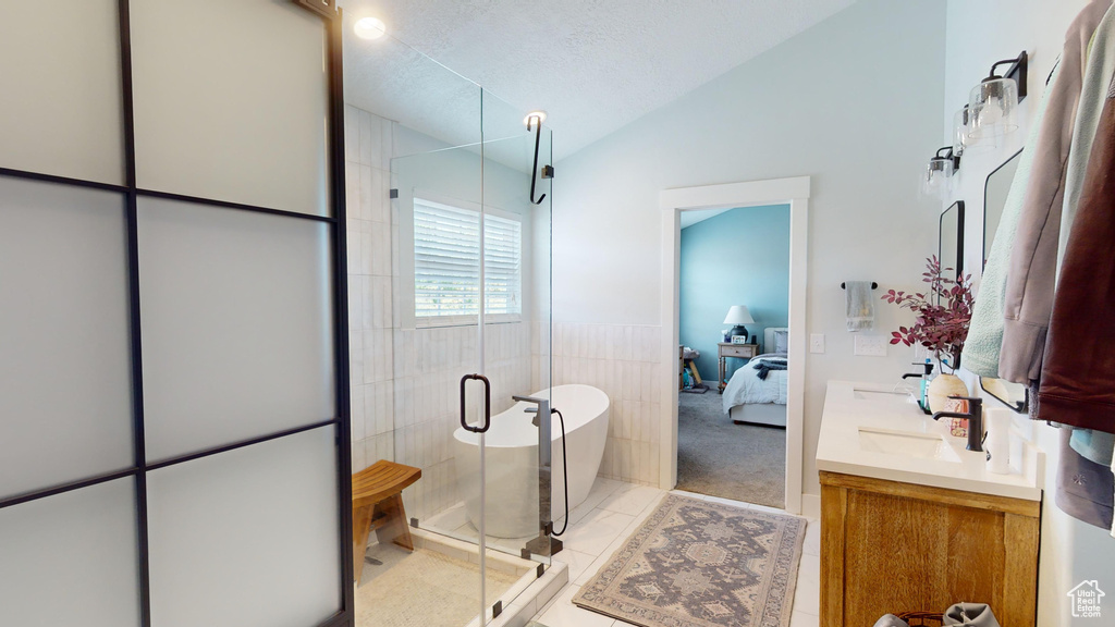 Bathroom with vaulted ceiling, tile walls, oversized vanity, tile flooring, and an enclosed shower