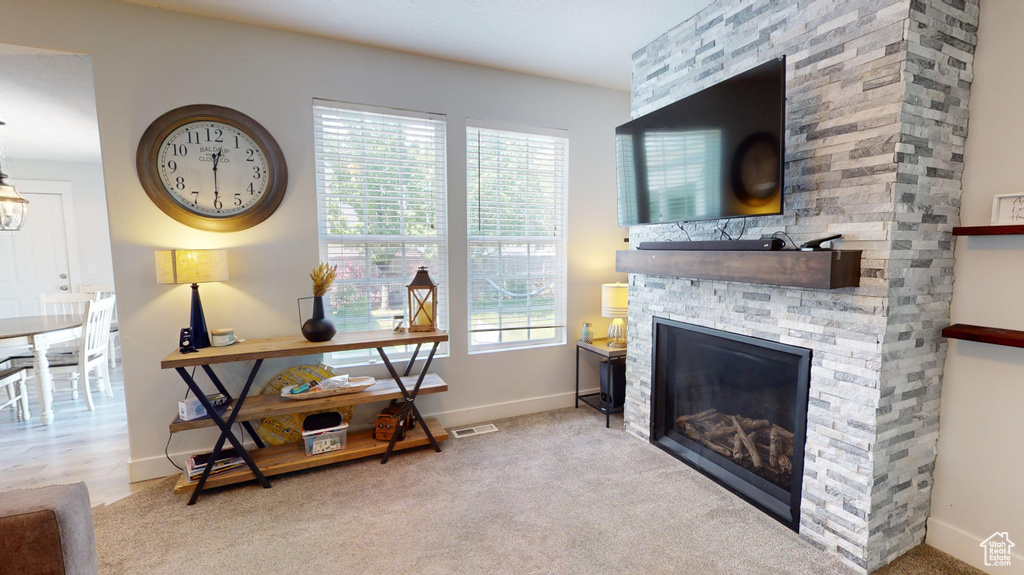 Carpeted living room with a stone fireplace and a healthy amount of sunlight