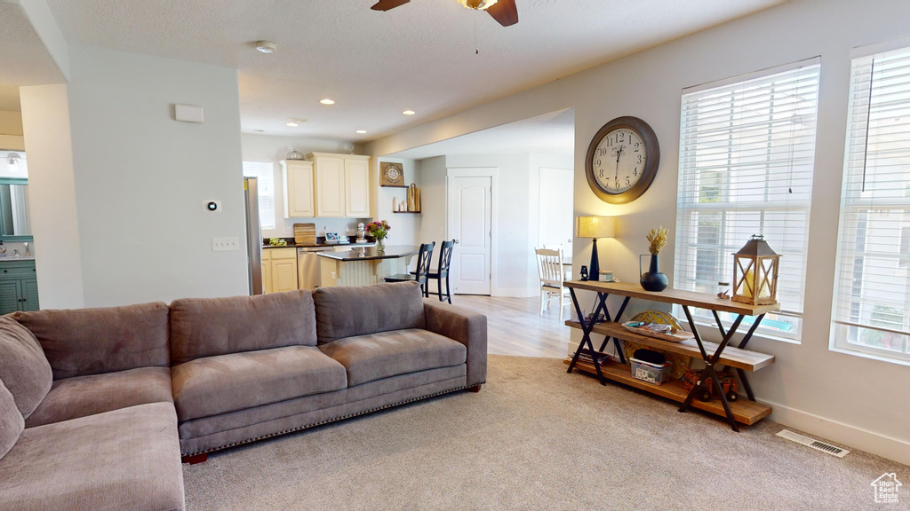 Carpeted living room with ceiling fan