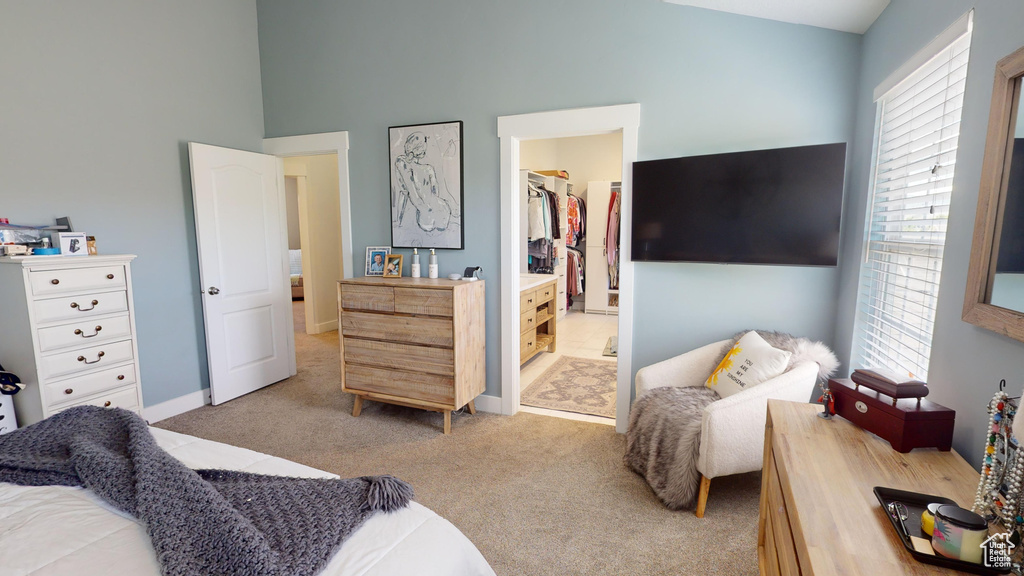 Carpeted bedroom with a high ceiling, a walk in closet, a closet, and ensuite bath