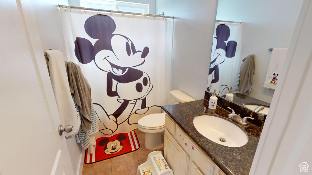 Bathroom with toilet, tile floors, and large vanity