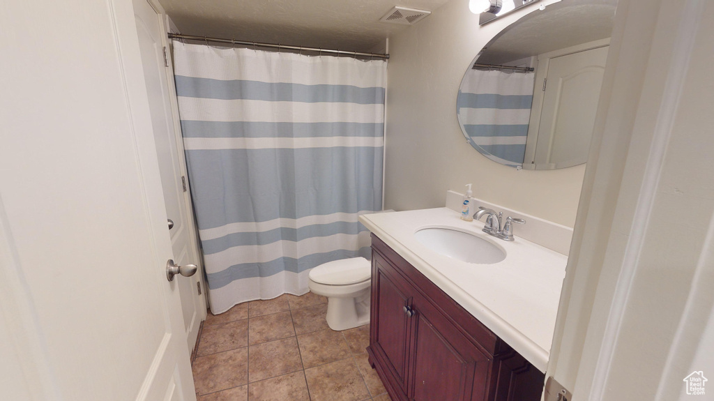 Bathroom featuring tile flooring, toilet, and large vanity