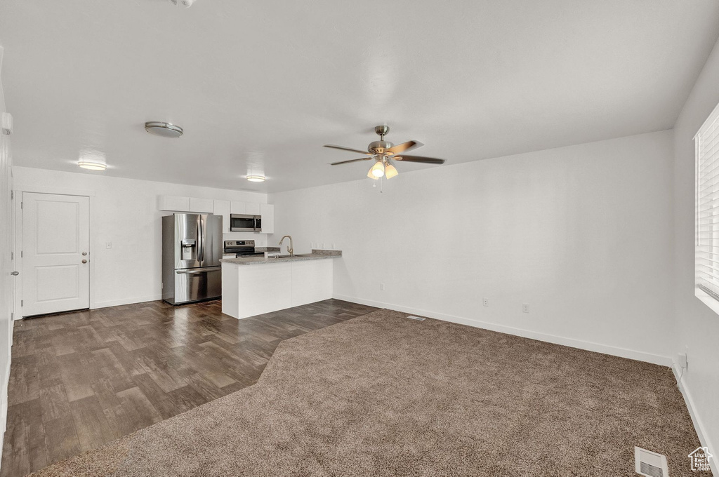 Unfurnished living room featuring sink, ceiling fan, and dark hardwood / wood-style flooring