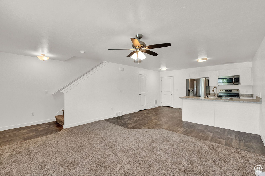 Unfurnished living room featuring dark carpet and ceiling fan