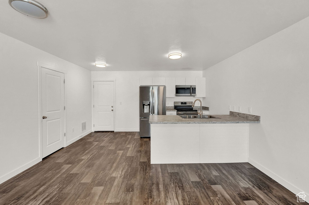 Kitchen with appliances with stainless steel finishes, sink, and dark wood-type flooring