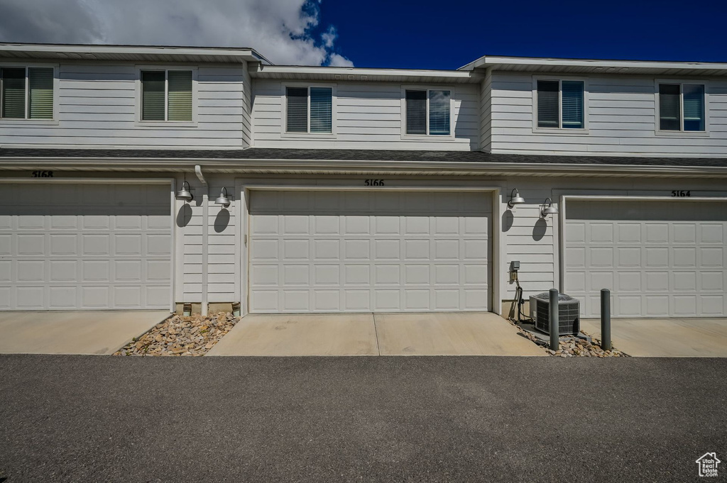 View of front of home with central AC and a garage