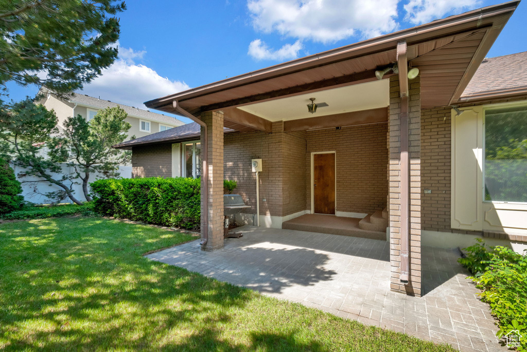 View of exterior entry featuring a patio and a yard