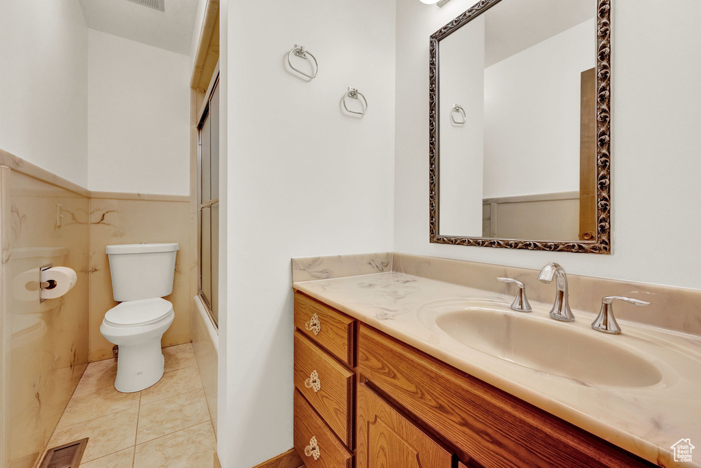 Full bathroom featuring tile flooring, enclosed tub / shower combo, vanity, and toilet