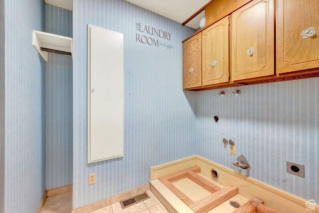 Laundry room with gas dryer hookup, hookup for an electric dryer, cabinets, and light tile floors