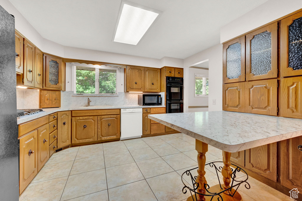 Kitchen with backsplash, black appliances, light tile floors, and plenty of natural light