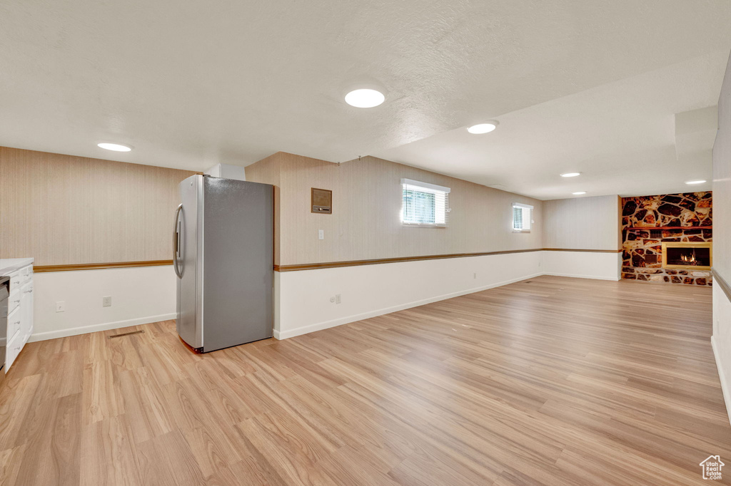 Unfurnished living room with a stone fireplace and light wood-type flooring