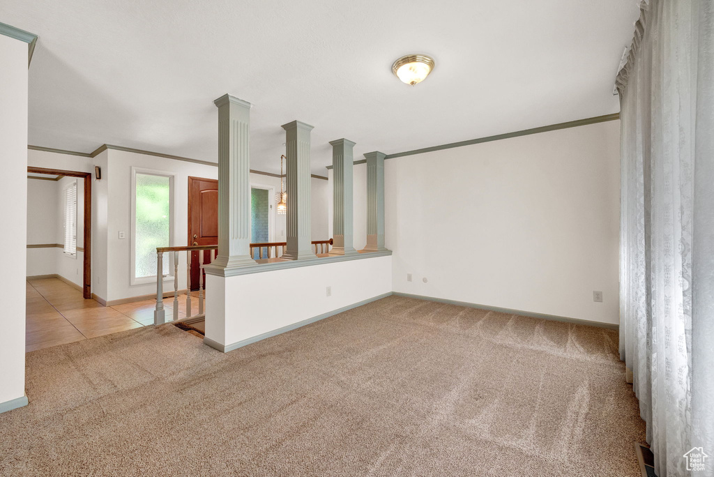 Unfurnished living room with carpet, crown molding, and decorative columns