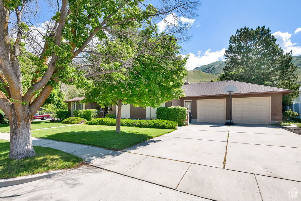 View of front of home with a garage, a mountain view, and a front lawn