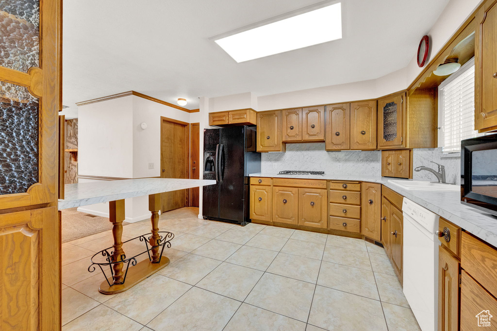 Kitchen with black fridge with ice dispenser, backsplash, white dishwasher, sink, and light tile floors